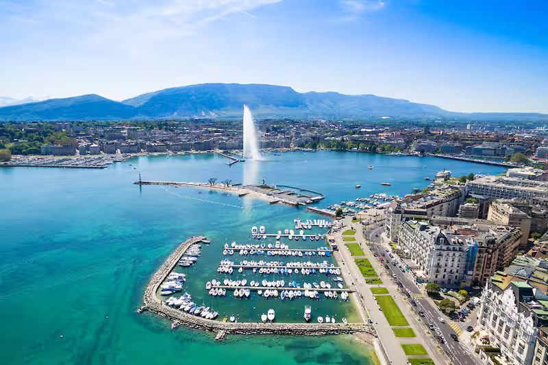View of the Jet d'Eau on Lake Geneva, Switzerland, featuring luxury lakeside hotels for corporate and diplomatic travel.